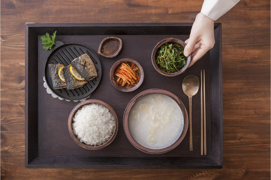 A bowl of bibimbap with various ingredients and a set of spoons and chopsticks
